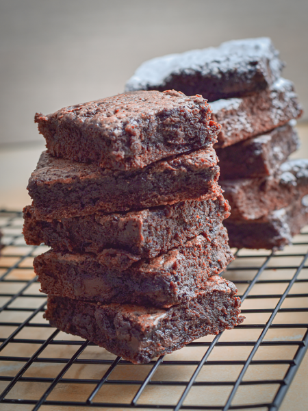 Freshly baked chocolate brownies stacked on a cooling rack, rich and tempting.